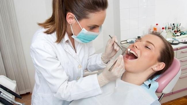 female dentist performing exam on female patient